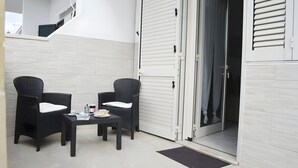 A balcony with two wicker chairs, a small table, and a sliding door. - Marylu' Holiday Home in Torre Specchia (Torre Specchia Ruggeri)