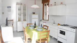Una cucina con tavolo da pranzo, sedie, frigorifero, lavatrice e fornello.