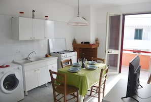 Une cuisine compacte équipée d’un lave-linge, d’un évier, d’une cuisinière et d’un coin repas avec une table dressée pour deux personnes.