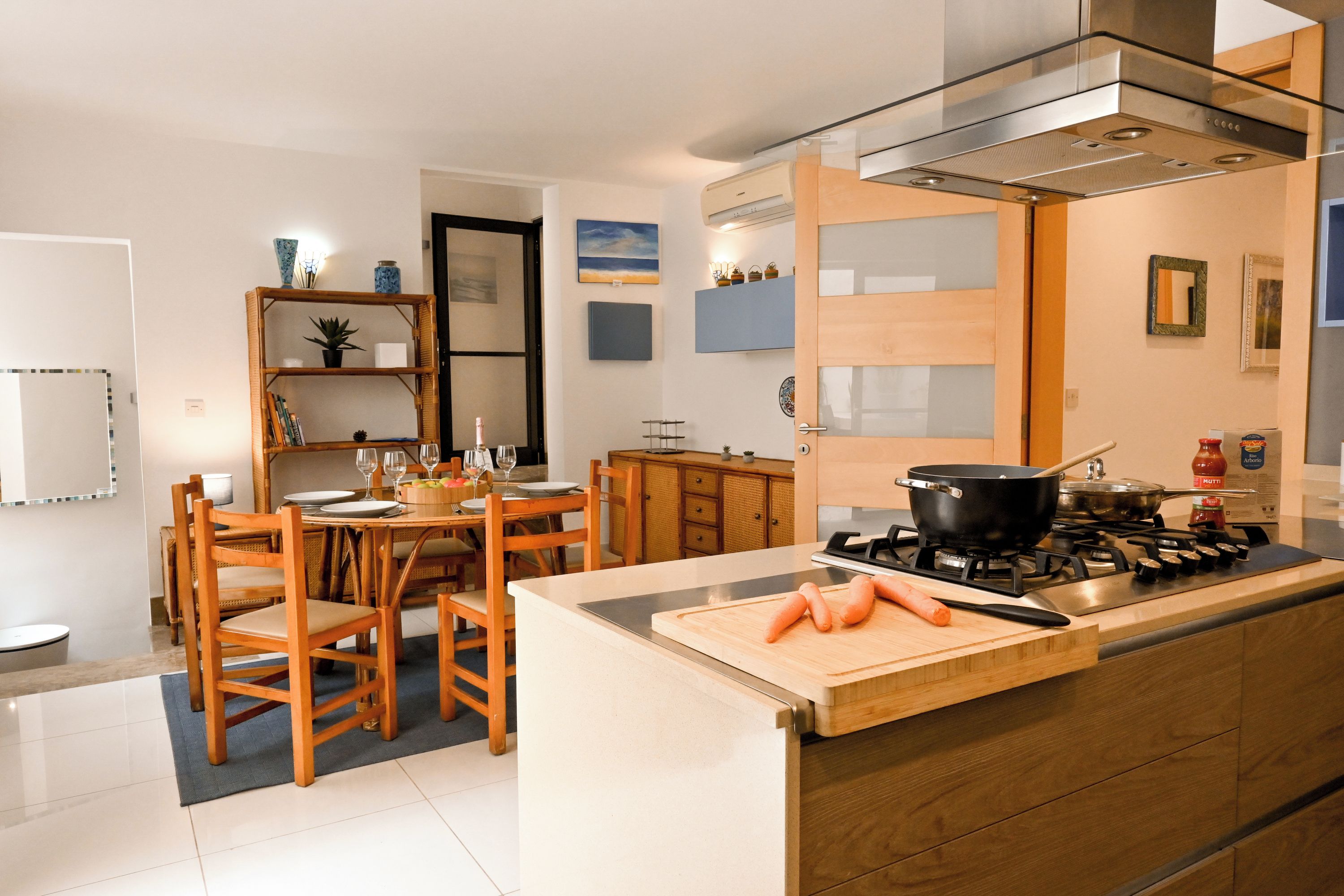 Una cocina moderna con una isla central, sillas de madera y una mesa de comedor.