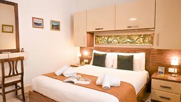 A hotel room with a bed, bedside tables, a desk, and a chair.