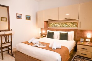 Una habitación de hotel con una cama, mesitas de noche, un escritorio y una silla.