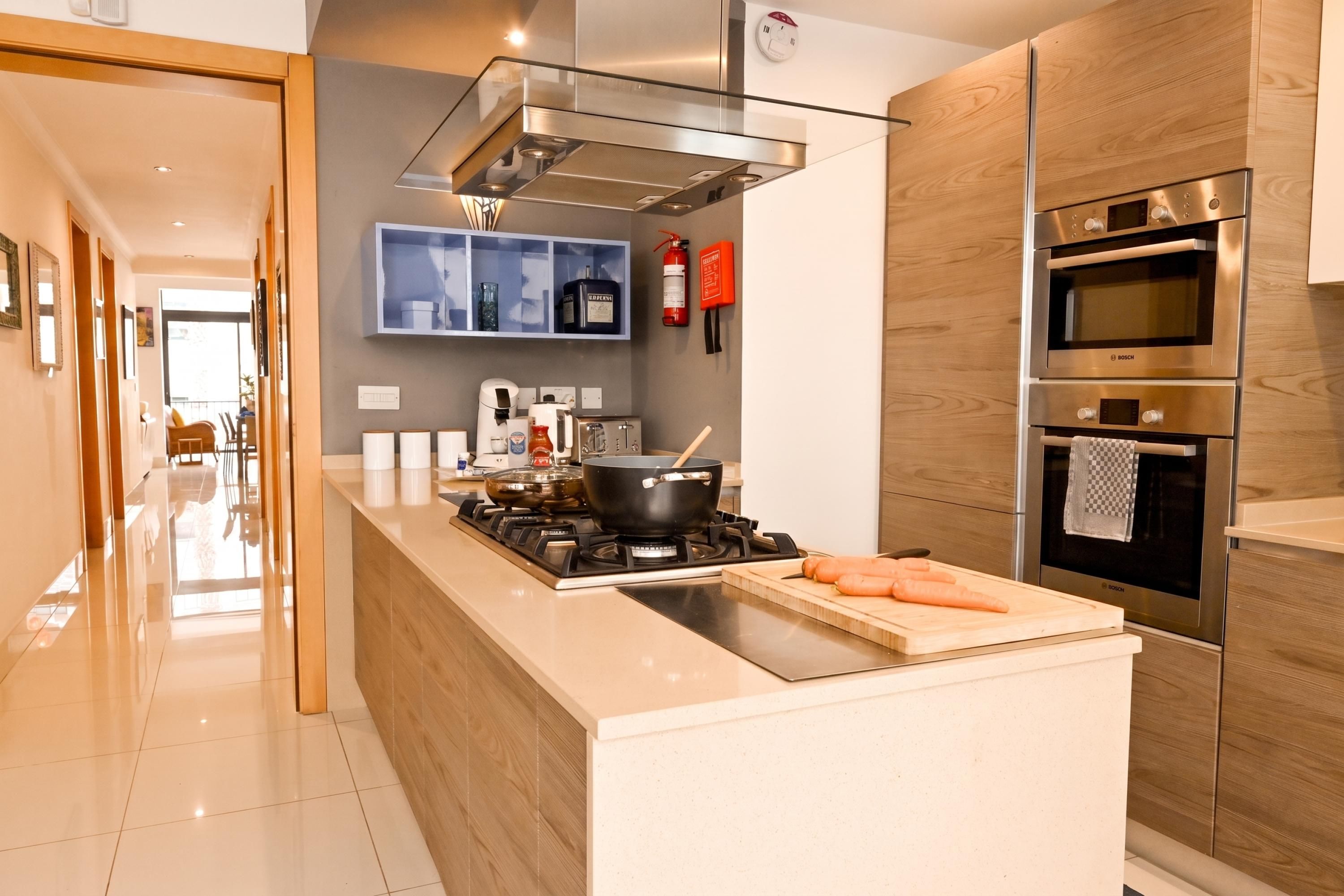 Una cucina moderna con isola centrale, forno integrato e cappa aspirante in acciaio inossidabile.
