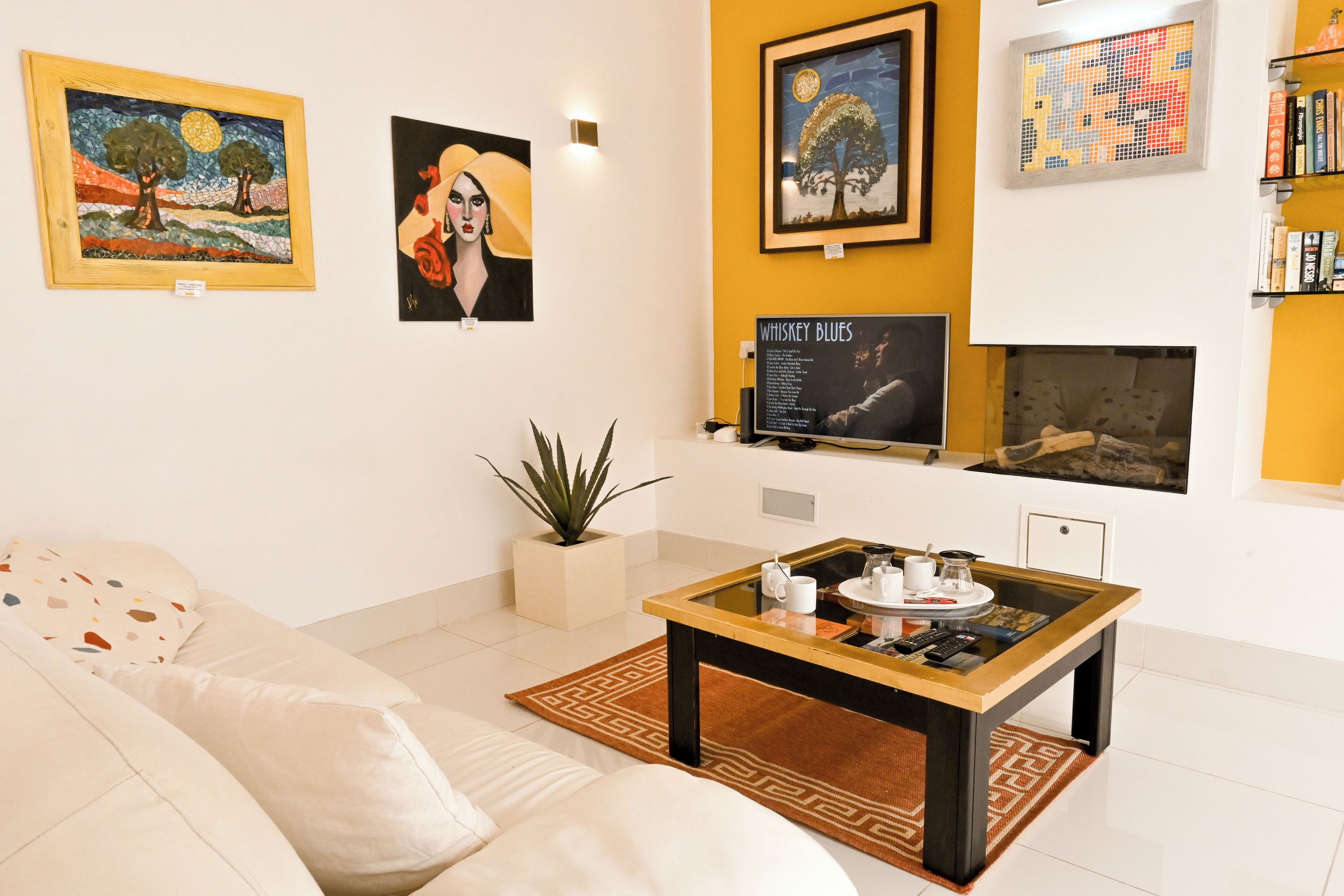 Una sala de estar con un sofá, una mesa de centro, obras de arte en las paredes y una chimenea.