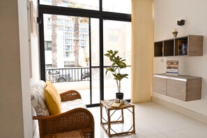 A modern living room with a sofa, a small table, a potted plant, and a bookshelf. - Modern & Terrace by the Beach, 3brd in Qawra (St. Paul's Bay)