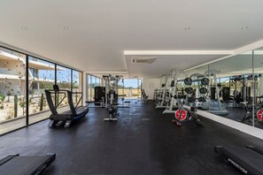 Un gimnasio con equipo de ejercicio, ventanas amplias y vistas al exterior.