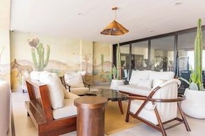 Ein modernes Wohnzimmer mit einer Couch, Sesseln, einem Couchtisch und einer Säulencactus-Pflanze.