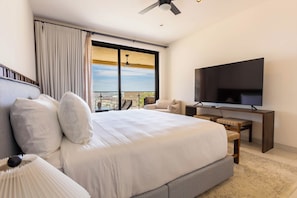 Ein Schlafzimmer mit einem großen Bett, einem Fernseher, einem Schreibtisch und Blick auf die Stadt.