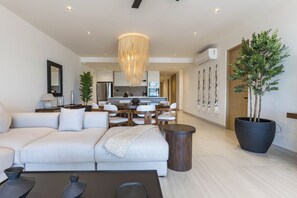 Ein modernes Wohnzimmer mit einer Couch, einem Couchtisch und einem Essbereich im Hintergrund.
