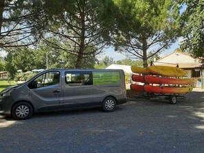 A silver van parked in a parking lot with a row of canoes on a trailer behind it. - Mobile home, pets welcome - 4 guests (Nonette-Orsonnette-Nonette)