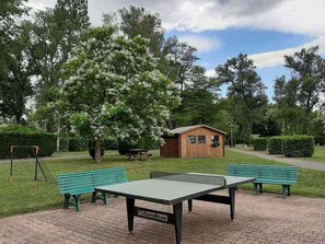 A park with a ping pong table, benches, a small shed, and a swing set.