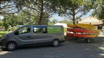 Una camioneta plateada estacionada en un estacionamiento, con una fila de canoas en un remolque detrás.