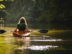 Une personne pratiquant le kayak sur une étendue d’eau calme, entourée d’une végétation luxuriante.
