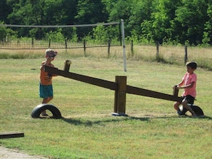 Une balançoire à deux places avec deux enfants dessus, dans un cadre extérieur.