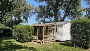 Eine kleine, eingeschossige Holzhütte mit Veranda und überdachter Sitzgelegenheit im Freien.
