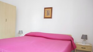 A bedroom with a bed, a nightstand, a lamp, a wardrobe, and a framed picture on the wall. - Chikai Holiday Home in San Foca LL56 (San Foca)