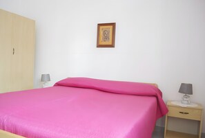 A bedroom with a bed, a nightstand, a lamp, a wardrobe, and a framed picture on the wall. - Chikai Holiday Home in San Foca LL56 (San Foca)