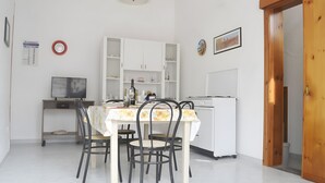 A kitchen with white cabinets, a dining table with chairs, a stove, and a refrigerator. - Chikai Holiday Home in San Foca LL56 (San Foca)