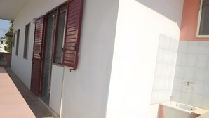 A corridor with a white wall, a red door, and a white sink. - Chikai Holiday Home in San Foca LL56 (San Foca)