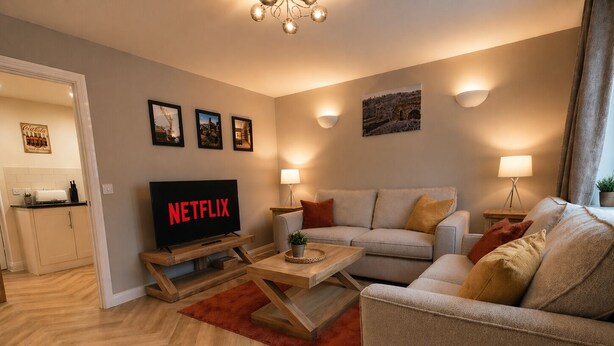 A modern living room with a sofa, coffee table, and a TV displaying 'NETFLIX'. - Central Bridgnorth Boutique Townhouse - Private Parking (Bridgnorth)