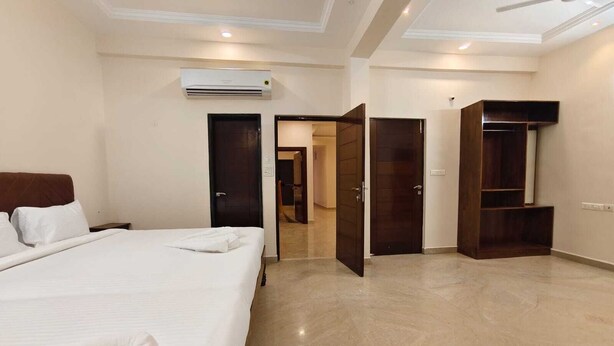 A hotel room with a bed, an air conditioning unit, a wardrobe, and a television. - Fortune Suites (Puducherry)
