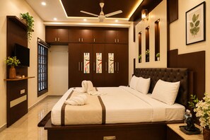 Une chambre à coucher avec un grand lit, un ventilateur de plafond et une armoire dotée de panneaux de verre décoratifs.