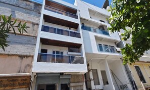 A multi-story building with balconies, a garage door, and a signboard. - Fortune Suites (Puducherry)