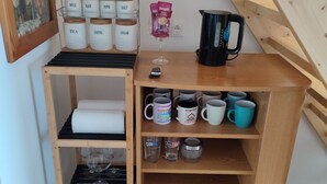 Uma estante de madeira com recipientes identificados para chá, café, açúcar, sal e especiarias.