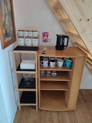 Un mueble de madera con recipientes etiquetados para té, café, azúcar, sal y especias.