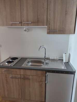 A kitchen with wooden cabinets, a stainless steel sink, a built-in stove, and a small refrigerator.