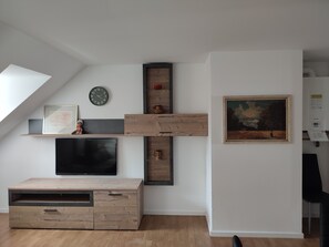 Una sala de estar moderna con televisor de pantalla plana, mueble de almacenamiento de madera y un cuadro en la pared.
