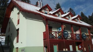 Um edifício com telhado vermelho, várias janelas e uma varanda com guarda-corpo.