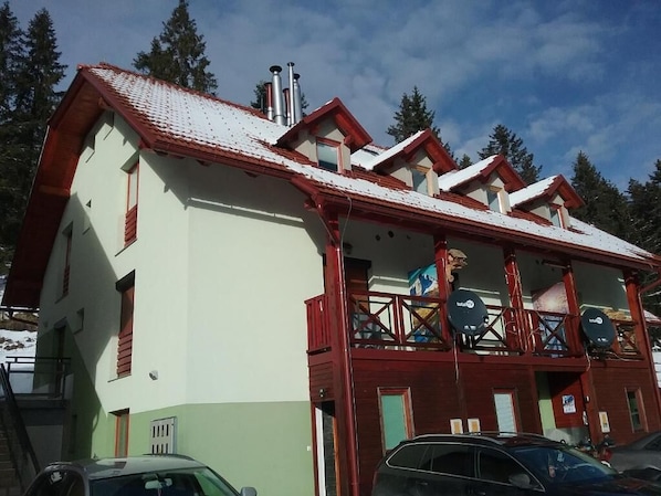 A building with a red roof, multiple windows, and a balcony with a railing.