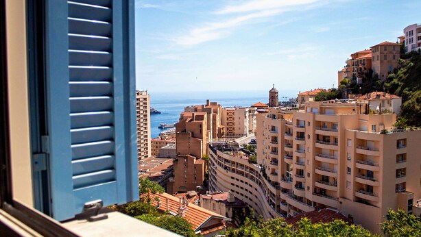 A coastal cityscape with multi-story buildings, balconies, and a clear view of the sea. - Appartement 6A - MyResidenced'Azur (Beausoleil)