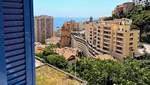 A coastal cityscape with multi-story buildings, a prominent tower, and a clear view of the sea. - Appartement 6A - MyResidenced'Azur (Beausoleil)