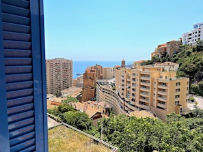A coastal cityscape with multi-story buildings, a prominent tower, and a clear view of the sea. - Appartement 6A - MyResidenced'Azur (Beausoleil)
