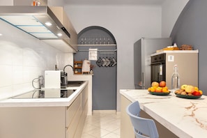 Una cucina moderna con forno a incasso, frigorifero e zona pranzo con una sedia.