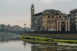 Une rivière où l’on peut voir des bateaux, un pont et des bâtiments historiques surmontés d’une tour horloge.