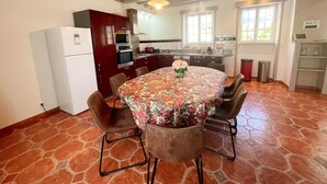 Un coin repas avec une table ronde, des chaises, un réfrigérateur et une cuisine en arrière-plan.