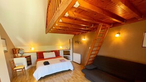 Une chambre aménagée en mezzanine comprenant un lit, un bureau, une chaise, un canapé et une échelle.
