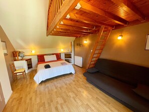 Ein Schlafzimmer im Loft-Stil mit Bett, Schreibtisch, Stuhl, einer Couch und einer Leiter.