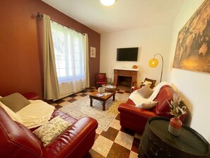 Ein Wohnzimmer mit Kamin, Ledersofas, einem Fernseher und einem Schachbrettfußboden.