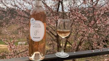 A bottle of wine and a glass on a balcony railing with cherry blossoms in the background.