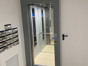 Ein Aufzug mit Bedienfeld, Türgriff und Stockwerkanzeige.