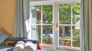 Ein Zimmer mit einem Bett, einem Fenster mit Blick ins Grüne und einem Fenstergriff.