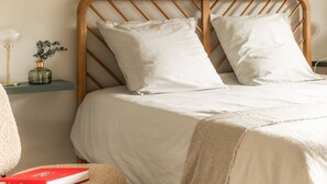 A bed with a wooden headboard, two pillows, a bedside table with a lamp, and a vase with flowers. - Renovated duplex near station - 6 guests (Arâches-la-Frasse)
