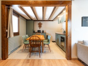 A compact kitchen with a dining area, wooden beams, and a window with curtains. - Renovated duplex near station - 6 guests (Arâches-la-Frasse)