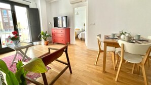 En moderne stue med spiseplads, tv og en balkon med planter.