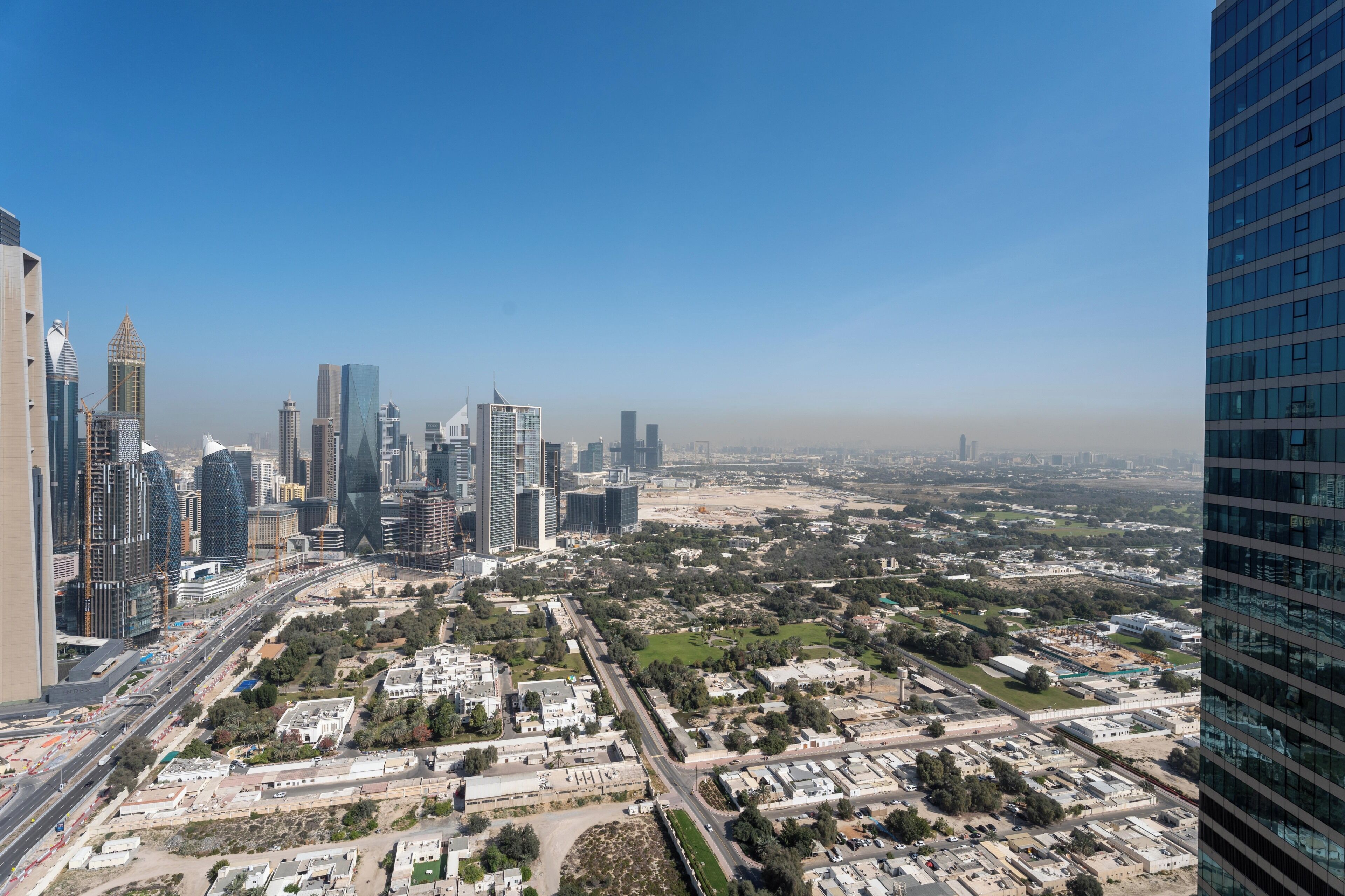 A cityscape with modern high-rise buildings, a clear sky, and a mix of urban and green spaces.