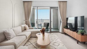 Un salon moderne avec un canapé, une table basse, un téléviseur et un balcon offrant une vue agréable.